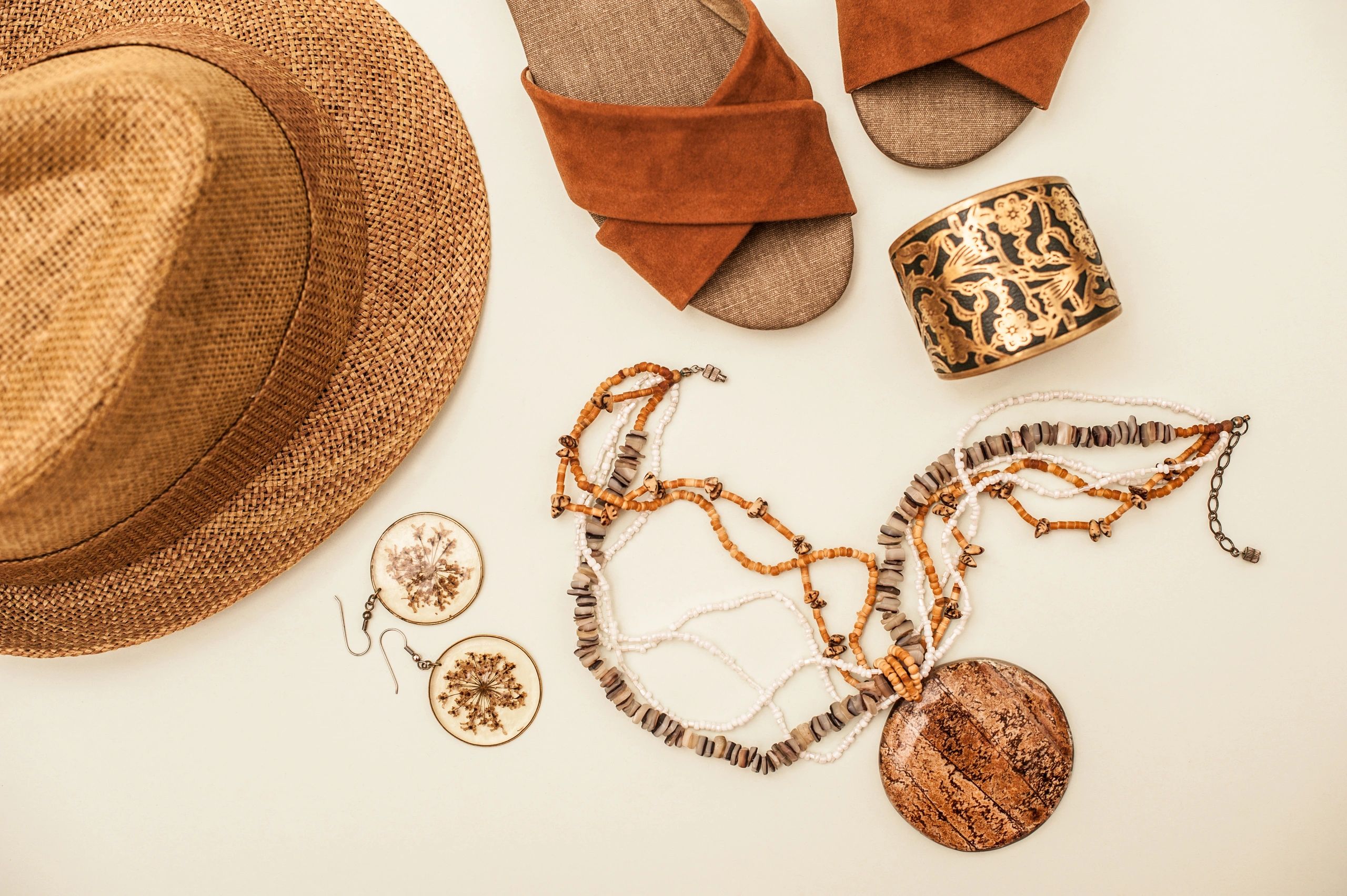 Elegant fashion accessories flatlay with sandals, jewelry, and hat